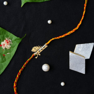 A beautifully handcrafted Rakhi with a Krishna feather, Bansuri, and "Radhe Radhe" written in silver, placed on a vibrant background with traditional Raksha Bandhan elements.